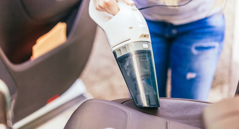 removing dog hair from car with a handheld vacuum